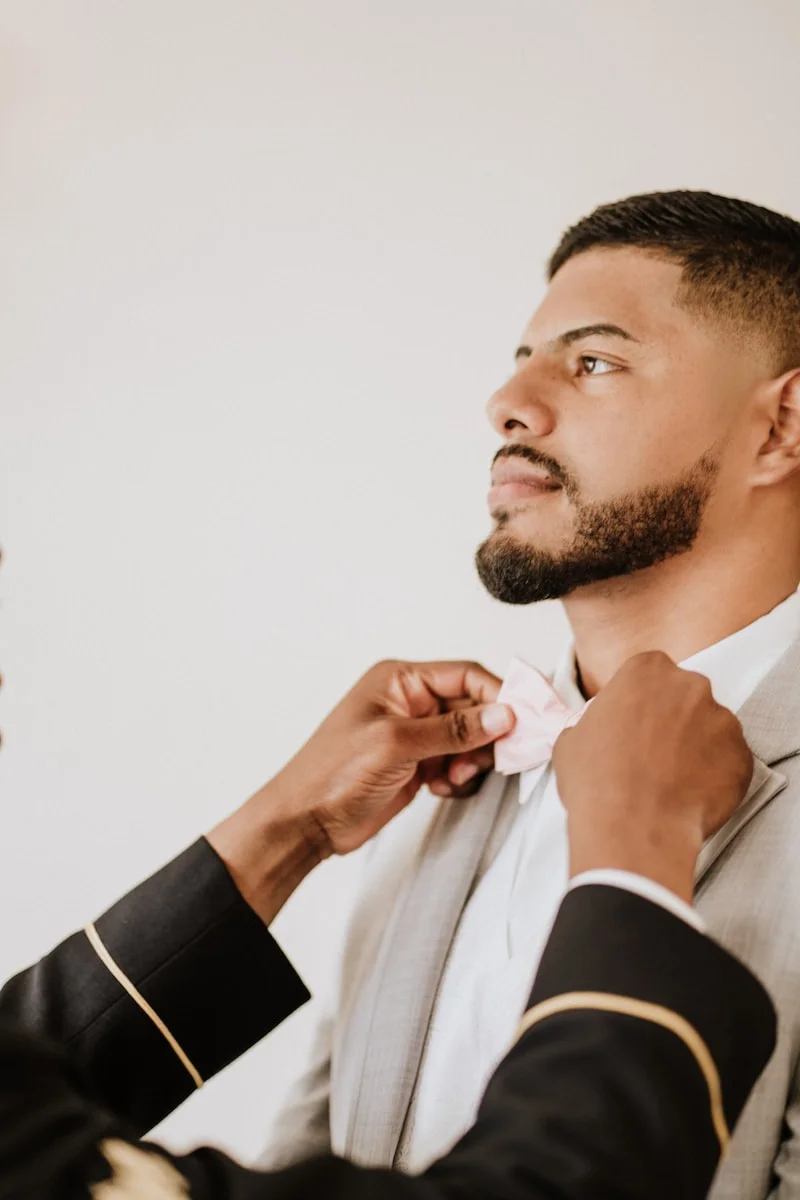 man in white coat and bowtie getting ready for a wedding