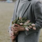 woman holding pink tulips wearing seasonal suits